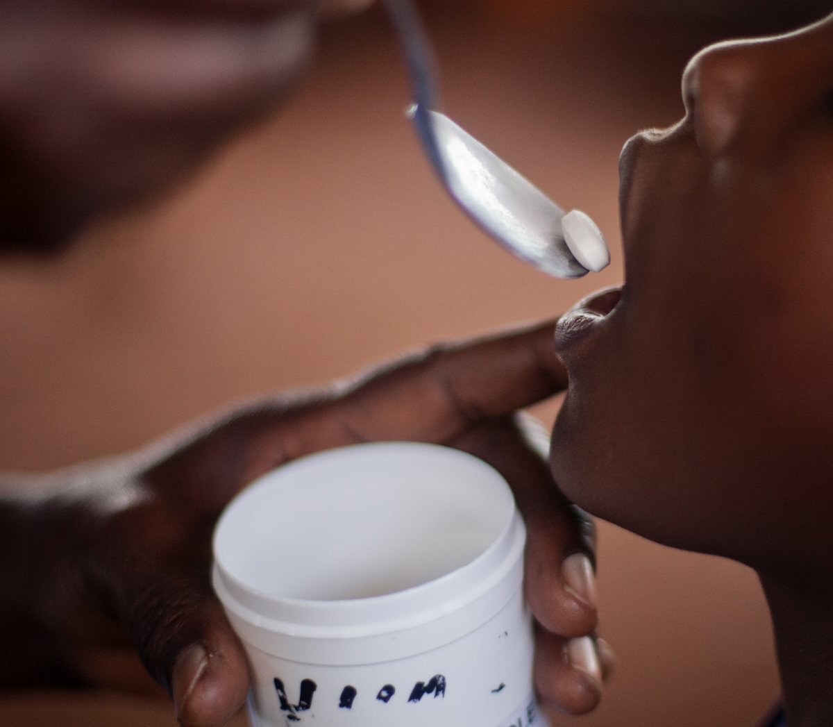 A child receiving a deworming tablet at a school deworming day in Kenya