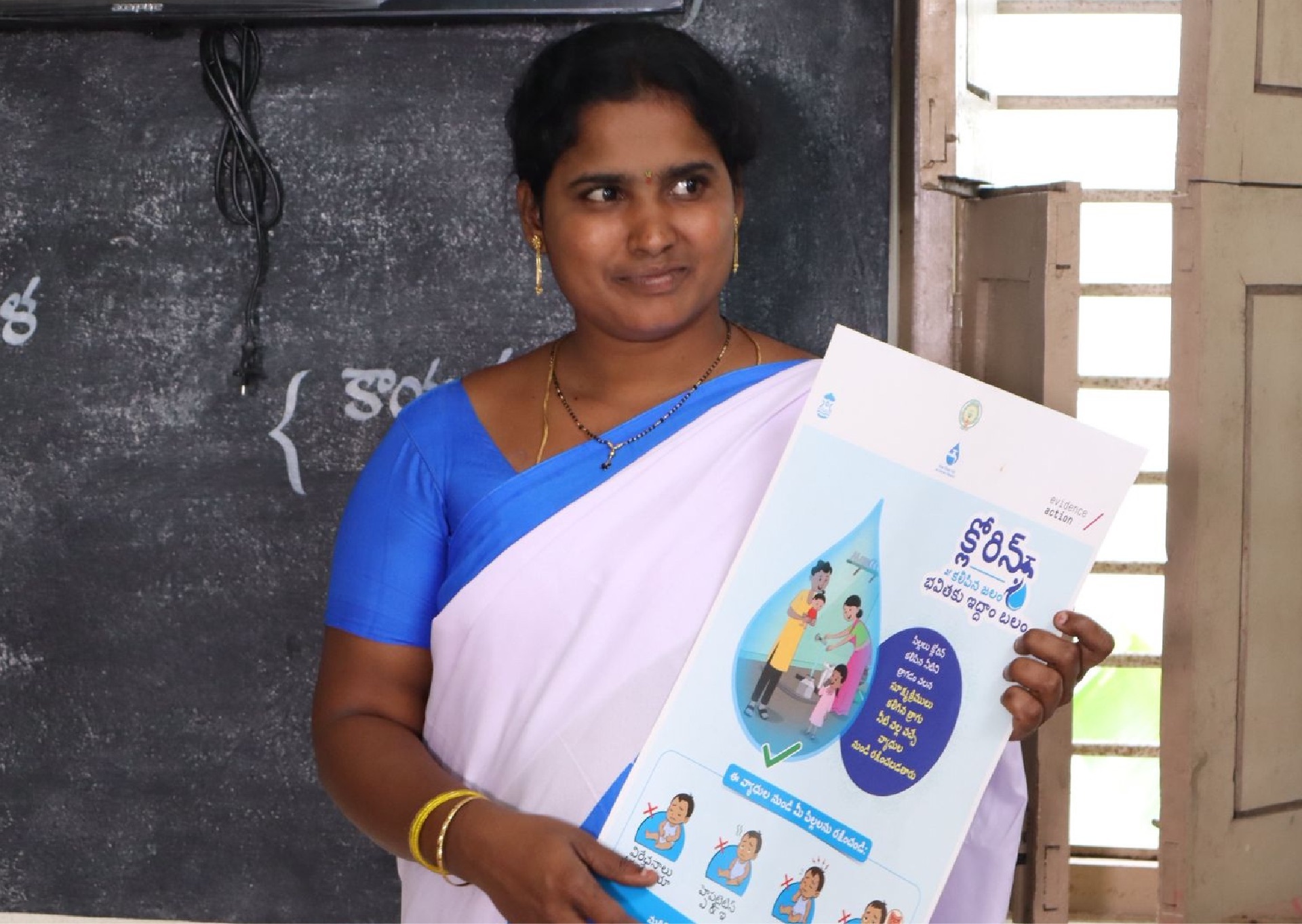 Krishnaveni holding educational materials about safe water at an Anganwadi center