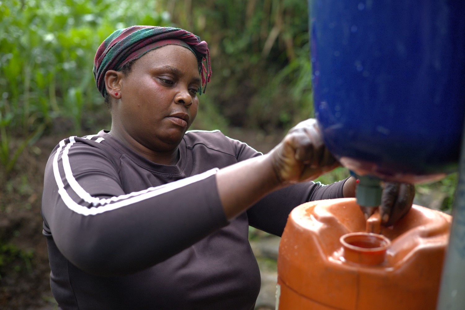 A community member collecting safe water from a chlorine dispenser installed by Evidence Action in rural Malawi